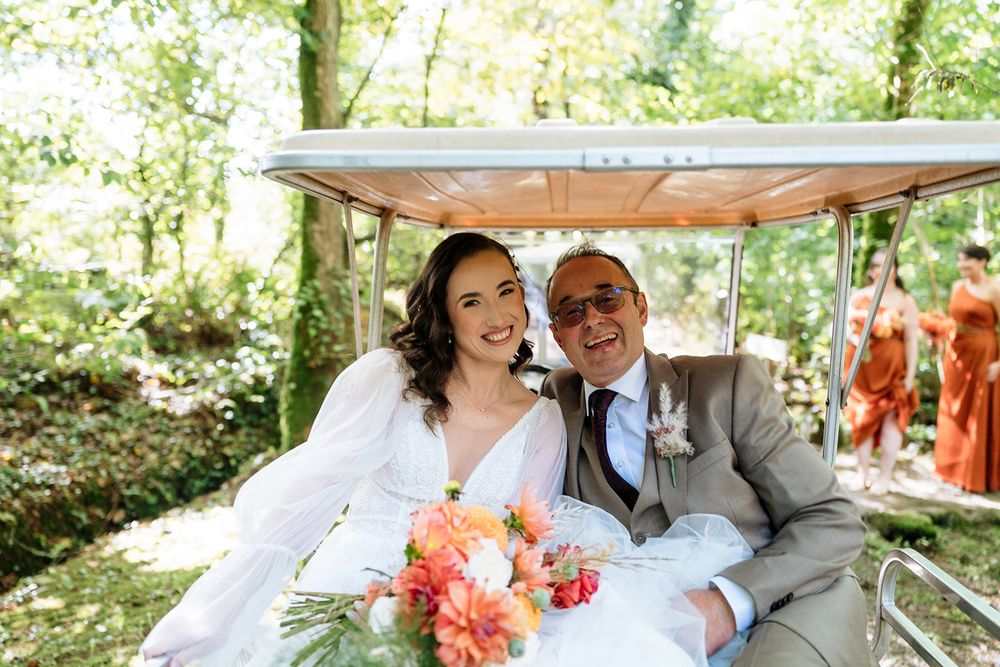 A couple shares a joyful moment while riding in a decorated wedding golf cart through a lush garden pathway.