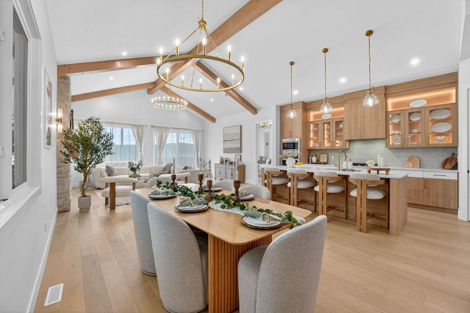 Elegant dining area with wooden beams and modern chandelier in an open concept space.