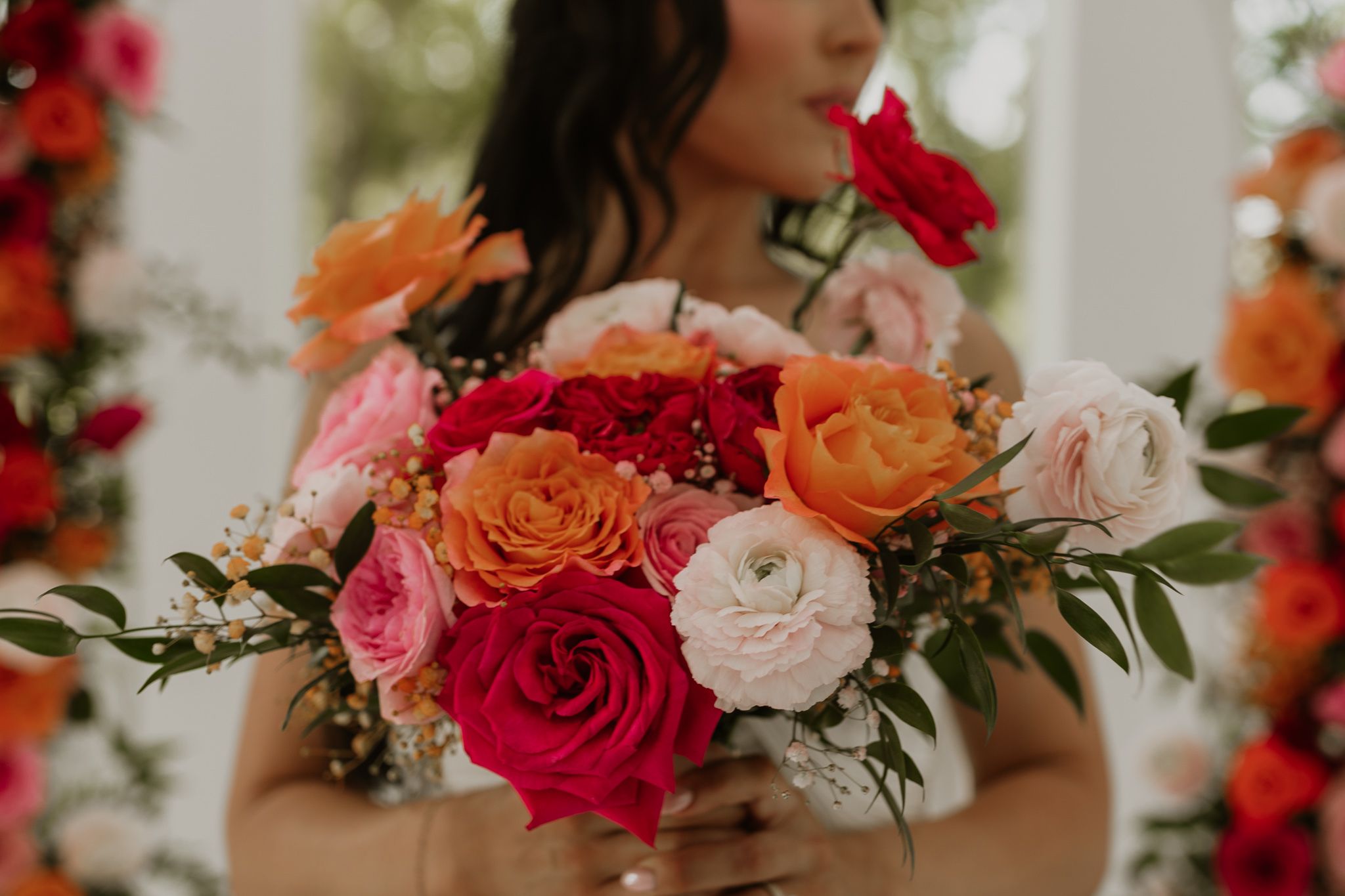 Vibrant bridal bouquet featuring red, orange, and pink roses with greenery captured during intimate elopement at Whitewood Ranch