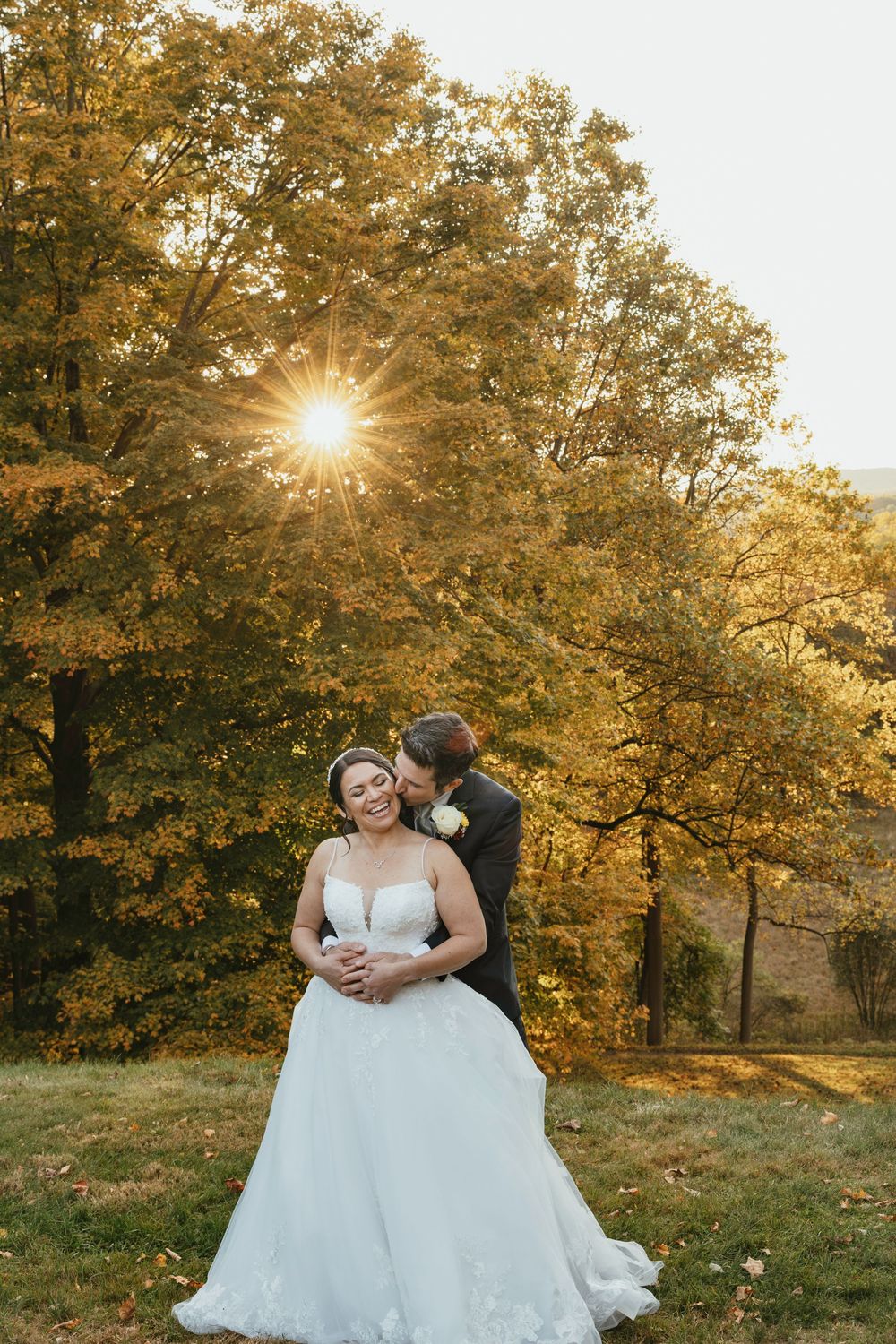A romantic sunset wedding photoshoot in a golden autumn field with trees glowing in warm evening light.