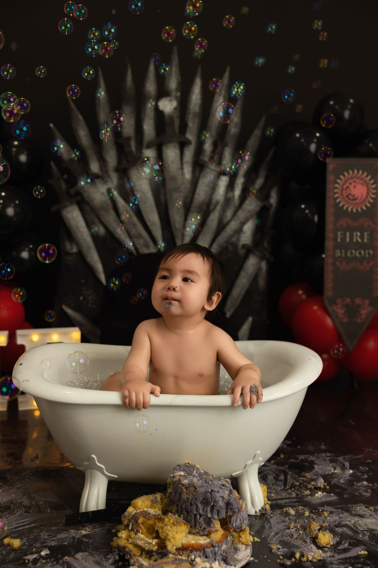 A child sits in a vintage white bathtub with bubbles and dark backdrop decorated with colorful lights and sparkles.