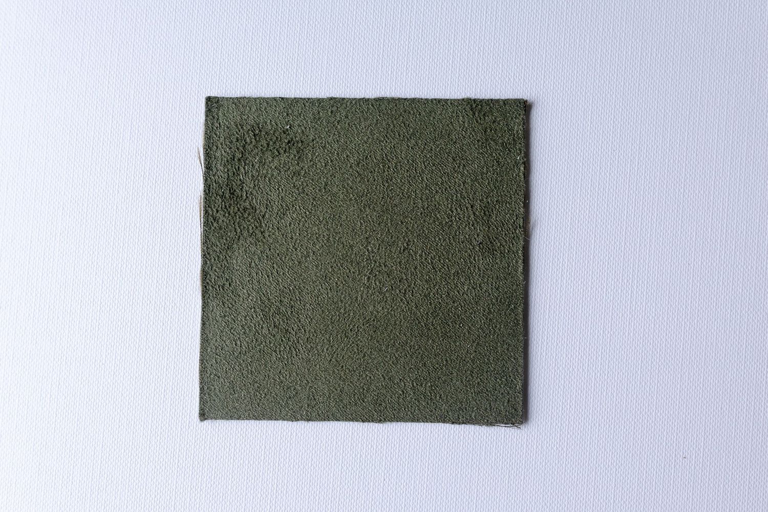 A square piece of olive green fabric or material against a white background.