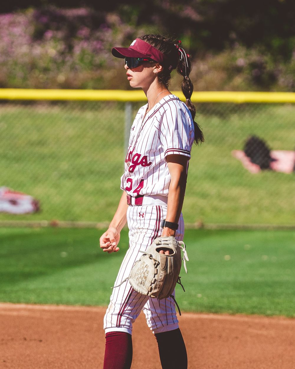 Baseball players in maroon and white striped uniforms standing on infield dirt during game.