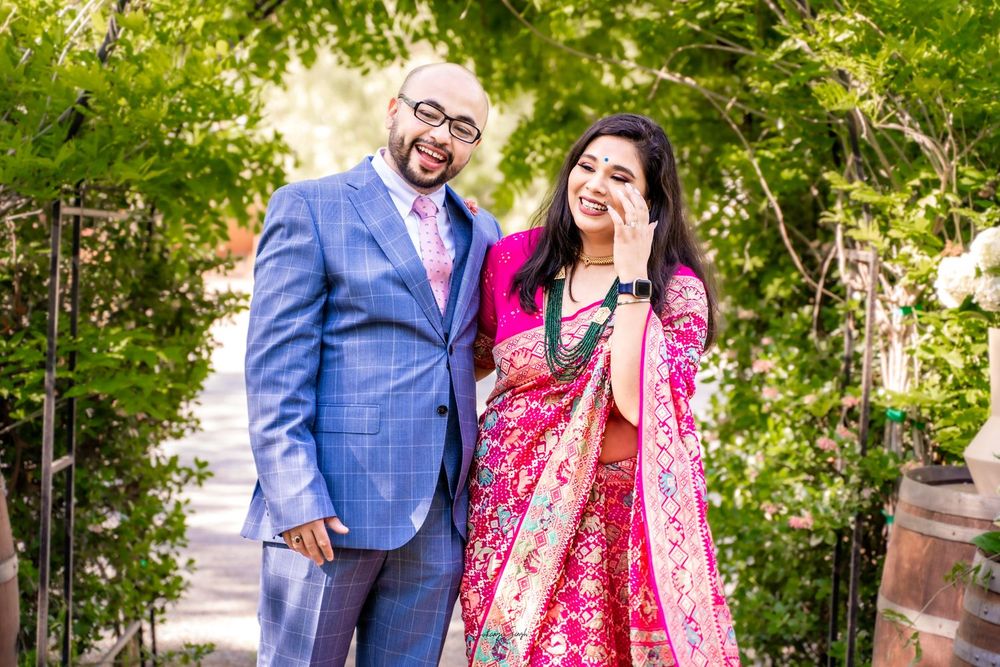 A couple in traditional wedding attire pose together in a lush garden setting during their celebration.