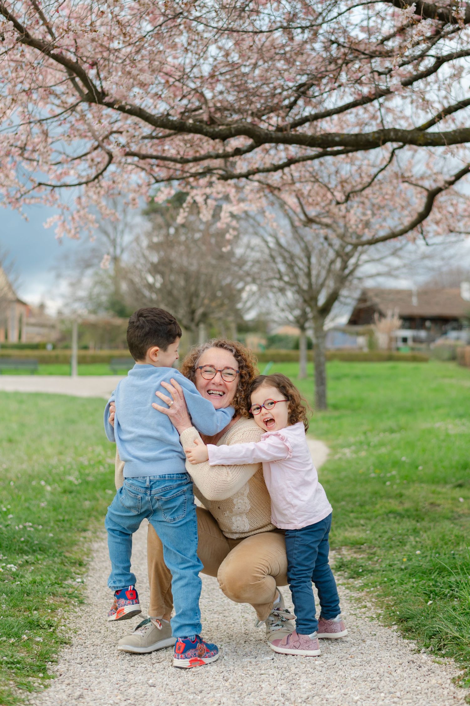 A joyful spring moment under blooming cherry trees on a grassy path with pink blossoms overhead.