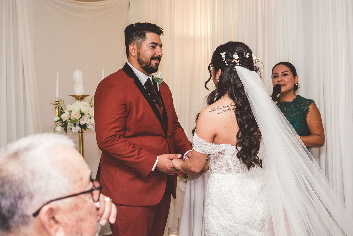 Wedding party members share joyful moments and laughter during a celebration in a white-draped venue.