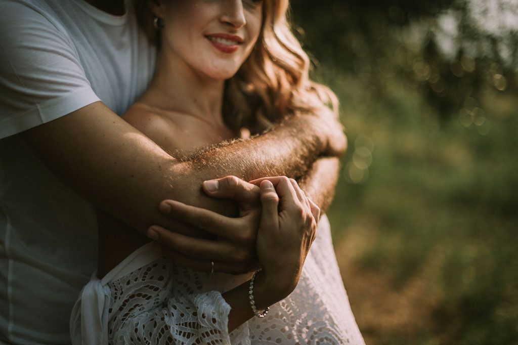 Couple shares tender moment in rustic outdoor setting with soft lighting.