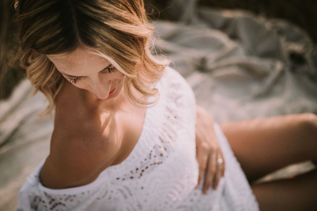 Romantic couple embraces in soft lighting while standing in a rustic outdoor setting at sunset.