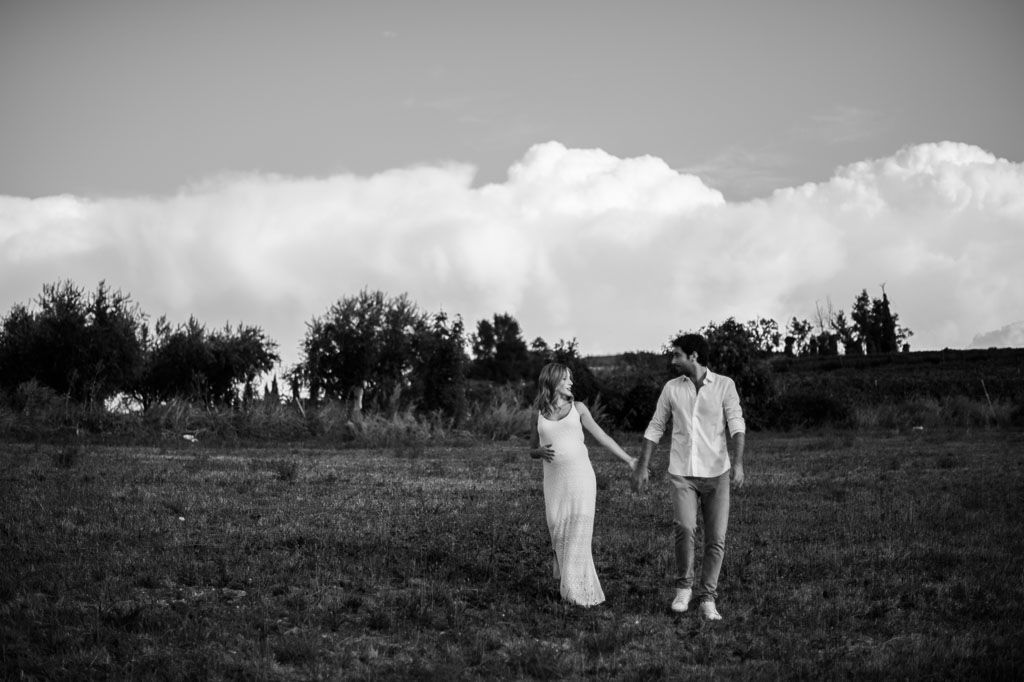 Silhouettes walking together across a grassy field under dramatic cloudy sky.