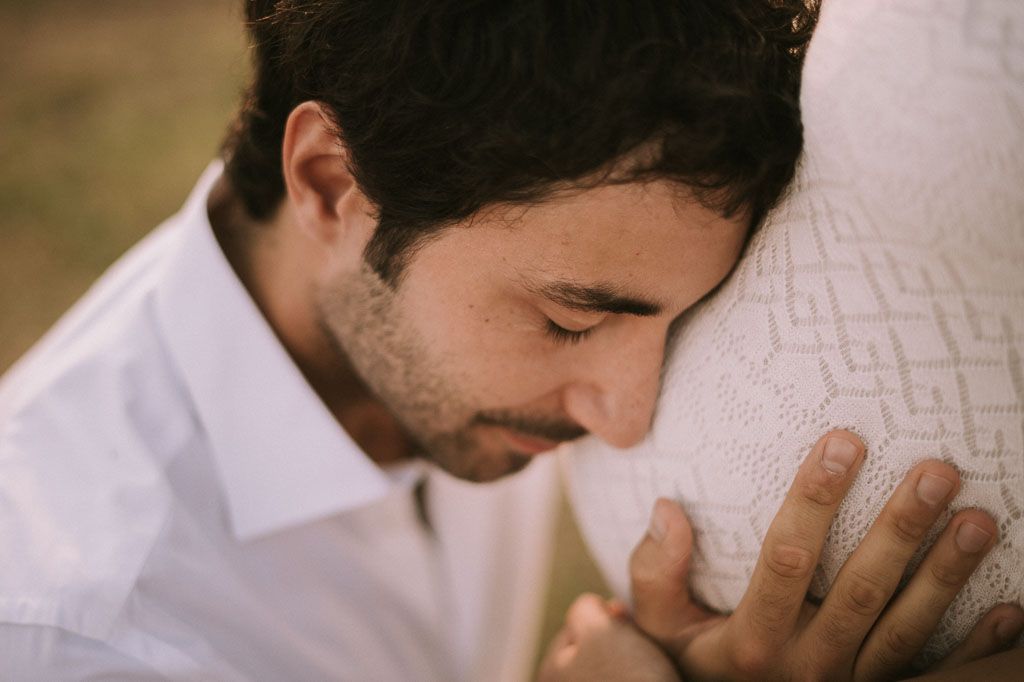 Close-up of intimate maternity moment between couple during outdoor photoshoot.