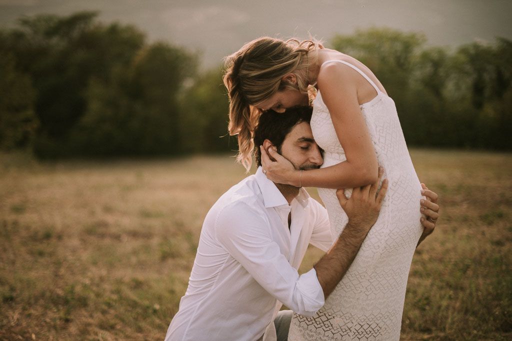 Tender moment captured between couple in white outfits during outdoor photoshoot.