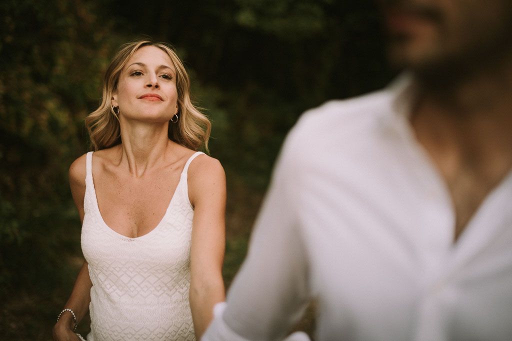 Couple in coordinating white outfits embrace during golden hour photography session.