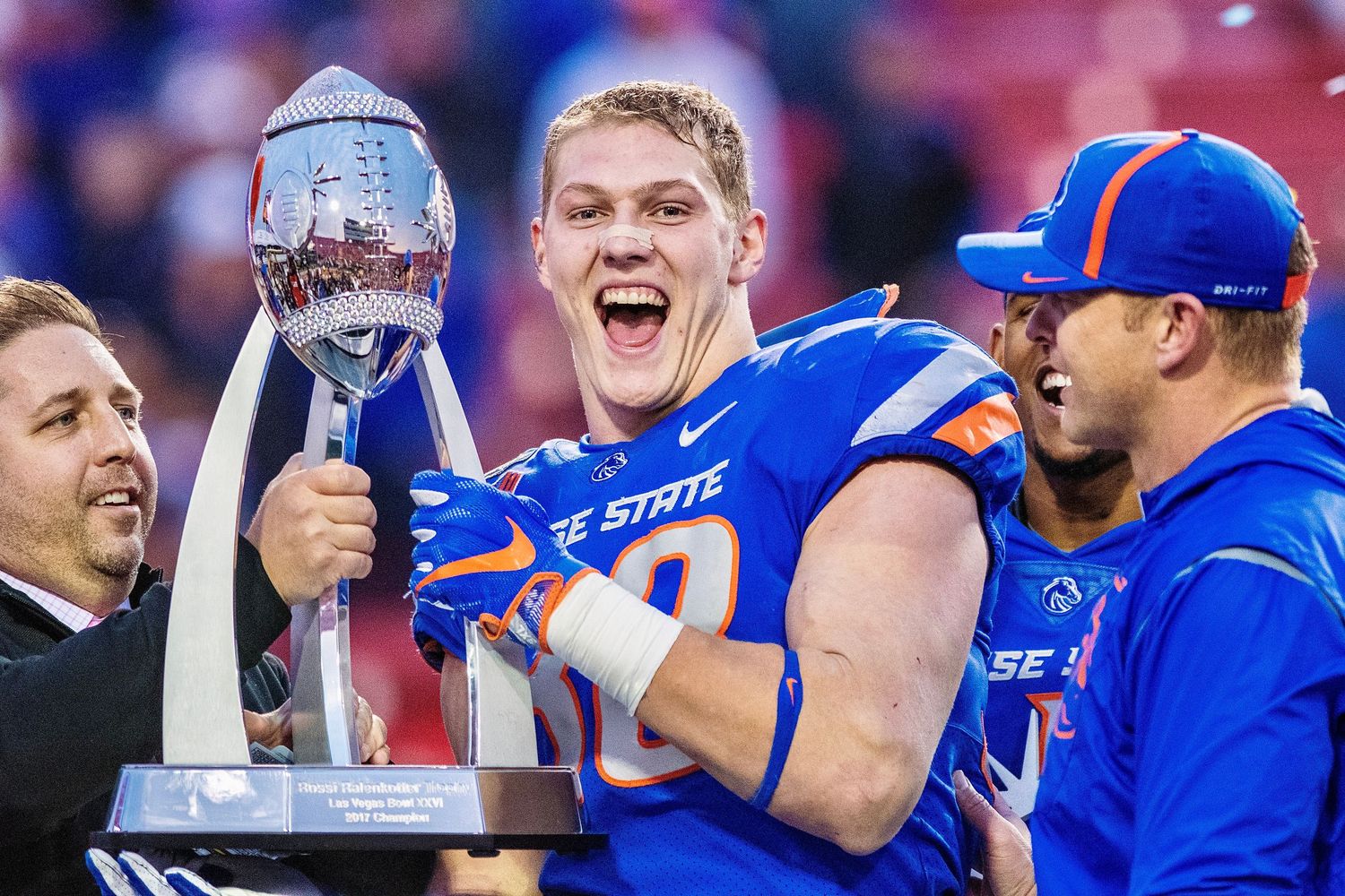 College football players celebrating with trophy after championship victory.