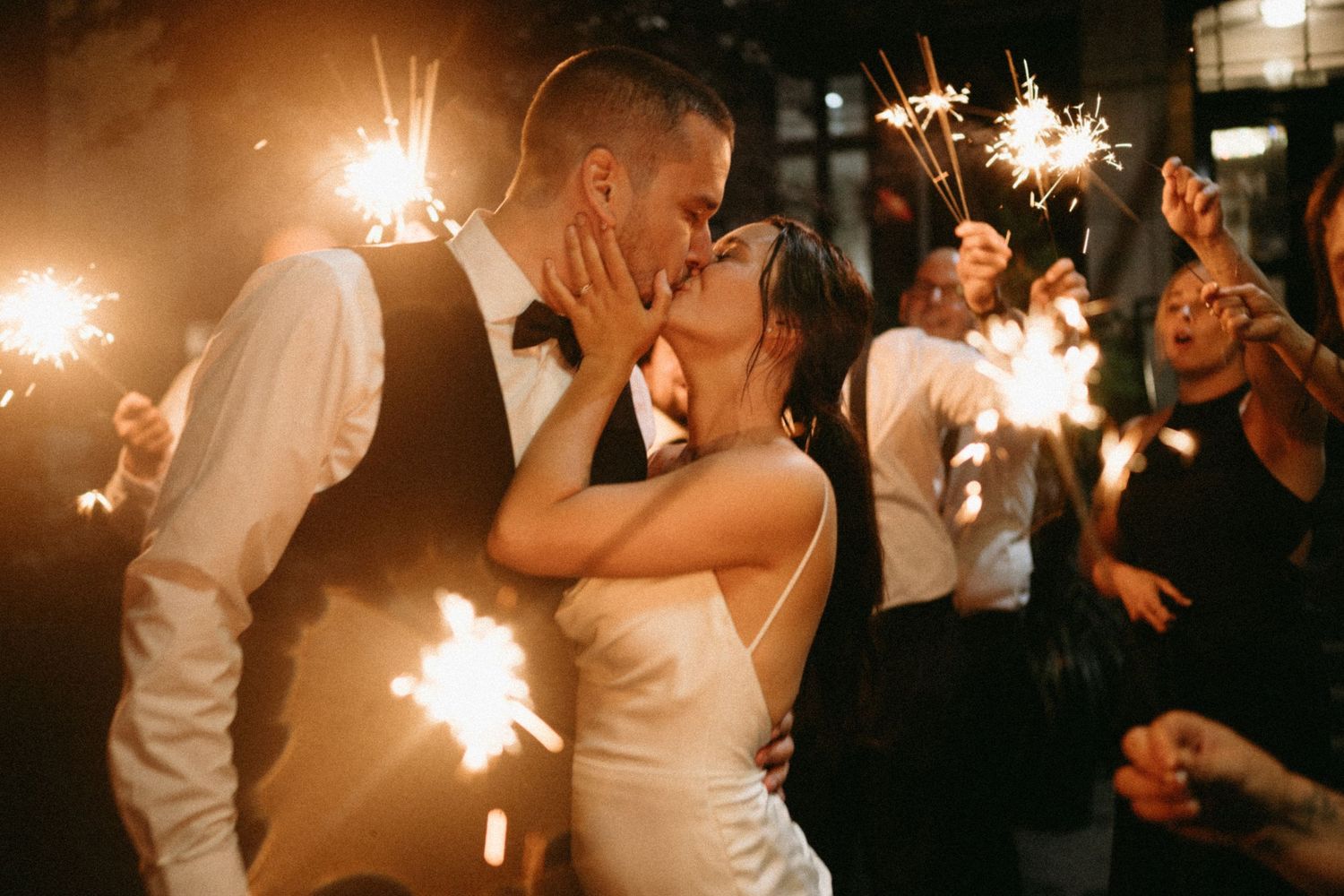A group of wedding attendants in black and white attire pose together outdoors with baby's breath bouquets.