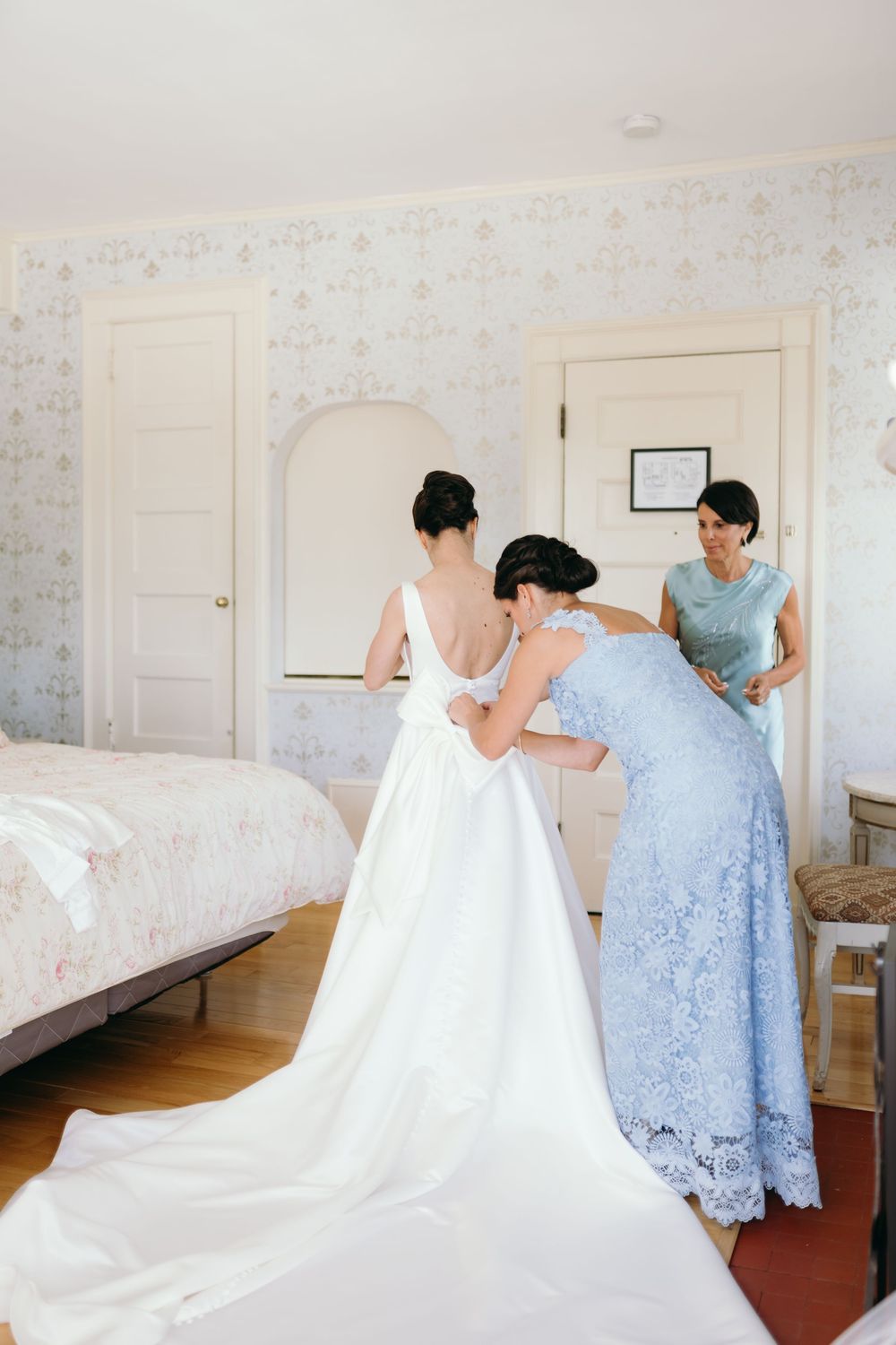 Series showing the preparation of a white wedding dress being laid out in a light-filled bedroom.