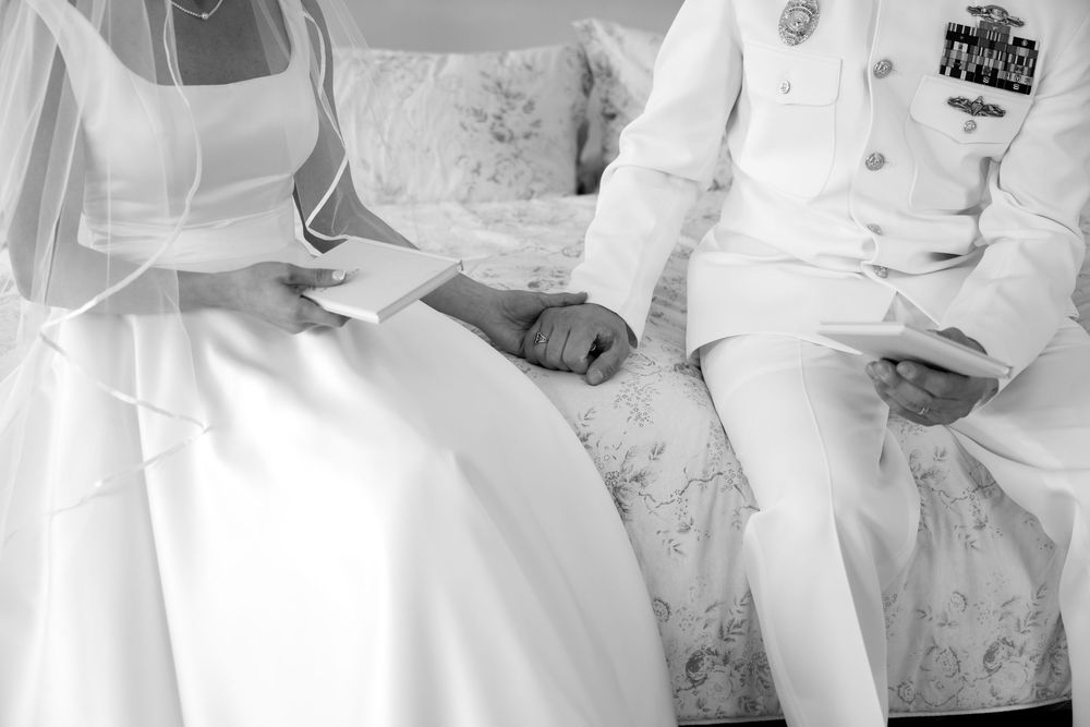 A couple in white formal attire sits together during their wedding celebration.
