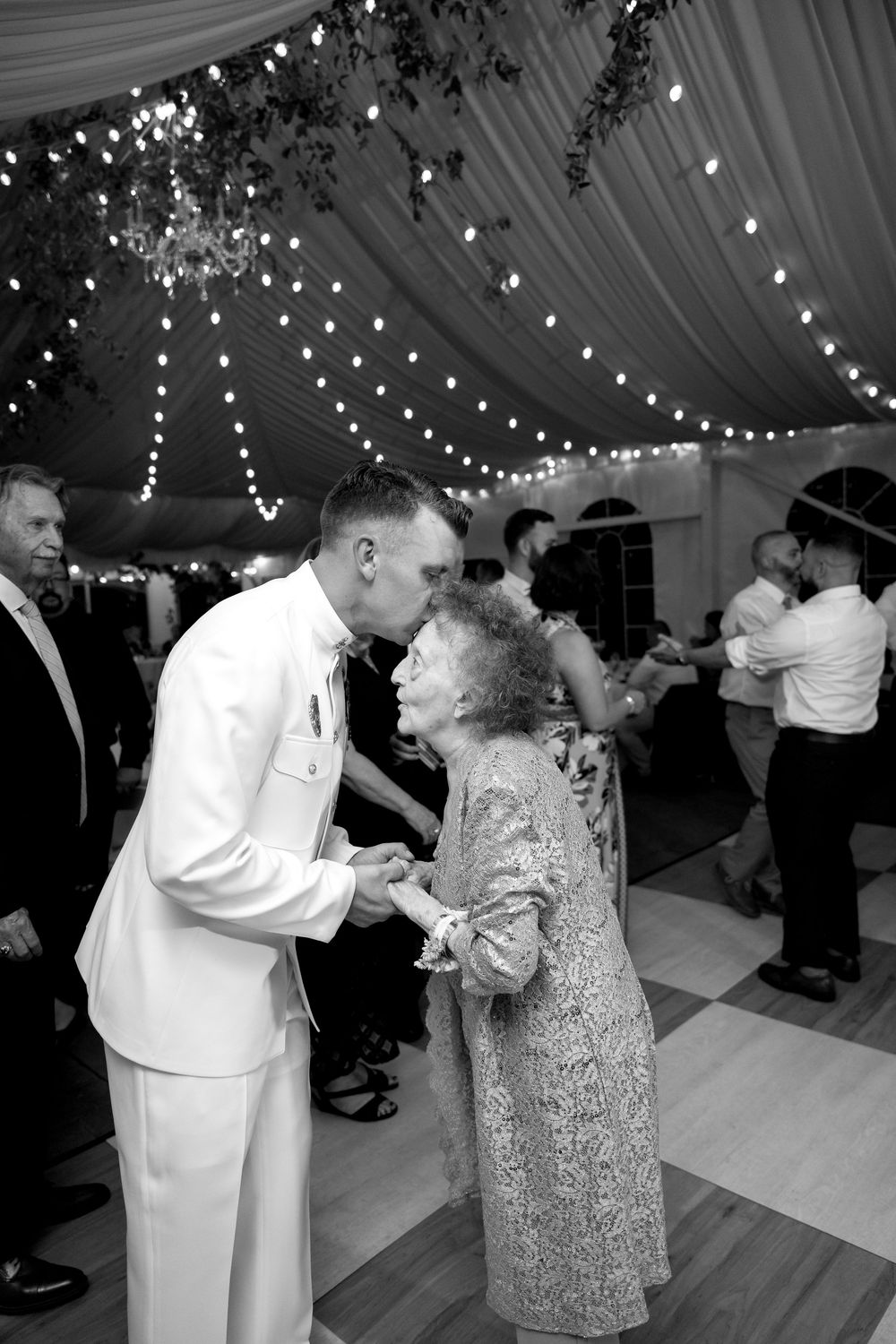 A couple shares a dance under elegant draped fabric and string lights at their reception.