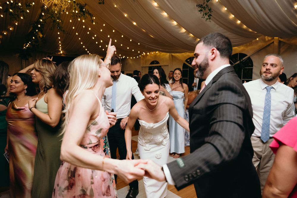 Wedding reception dance floor with string lights and guests enjoying the celebration.