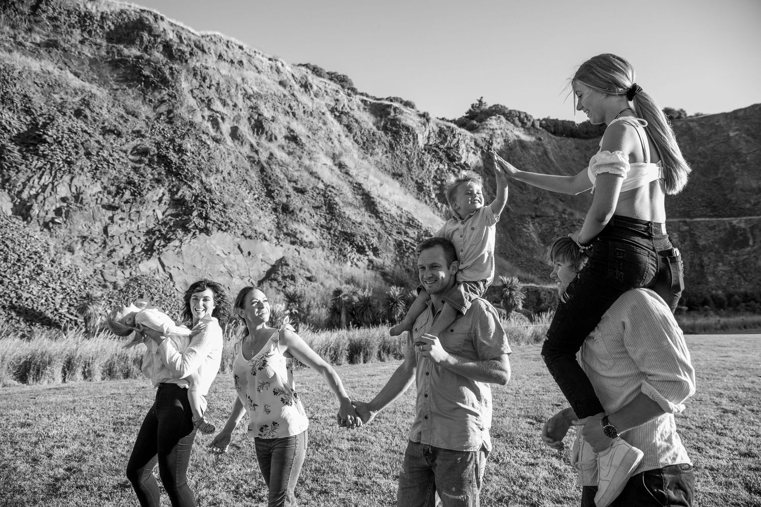 A black and white photo showing people dancing and twirling joyfully together in a scenic mountain landscape.