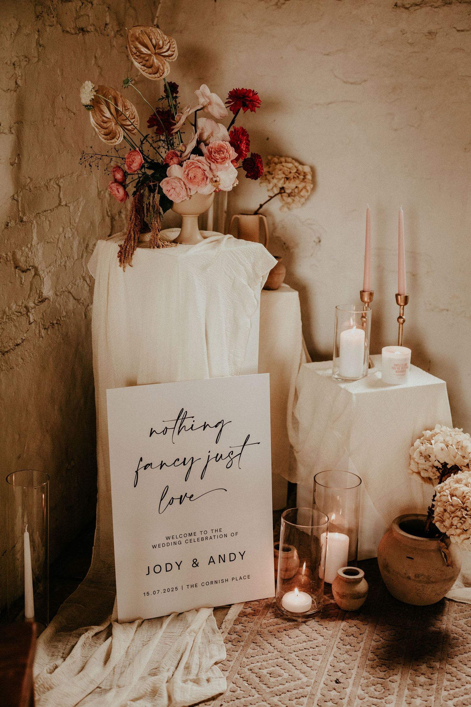 Romantic wedding decor with pink roses, candles and a sign reading 'nothing fancy just love' in rustic setting.