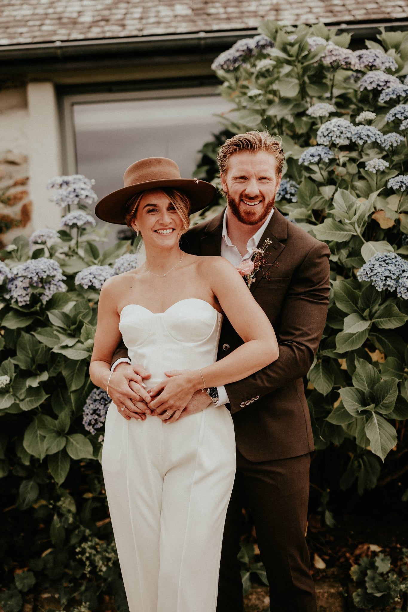A romantic wedding photo series showing a couple in formal attire posing together outdoors with white hydrangea flowers.