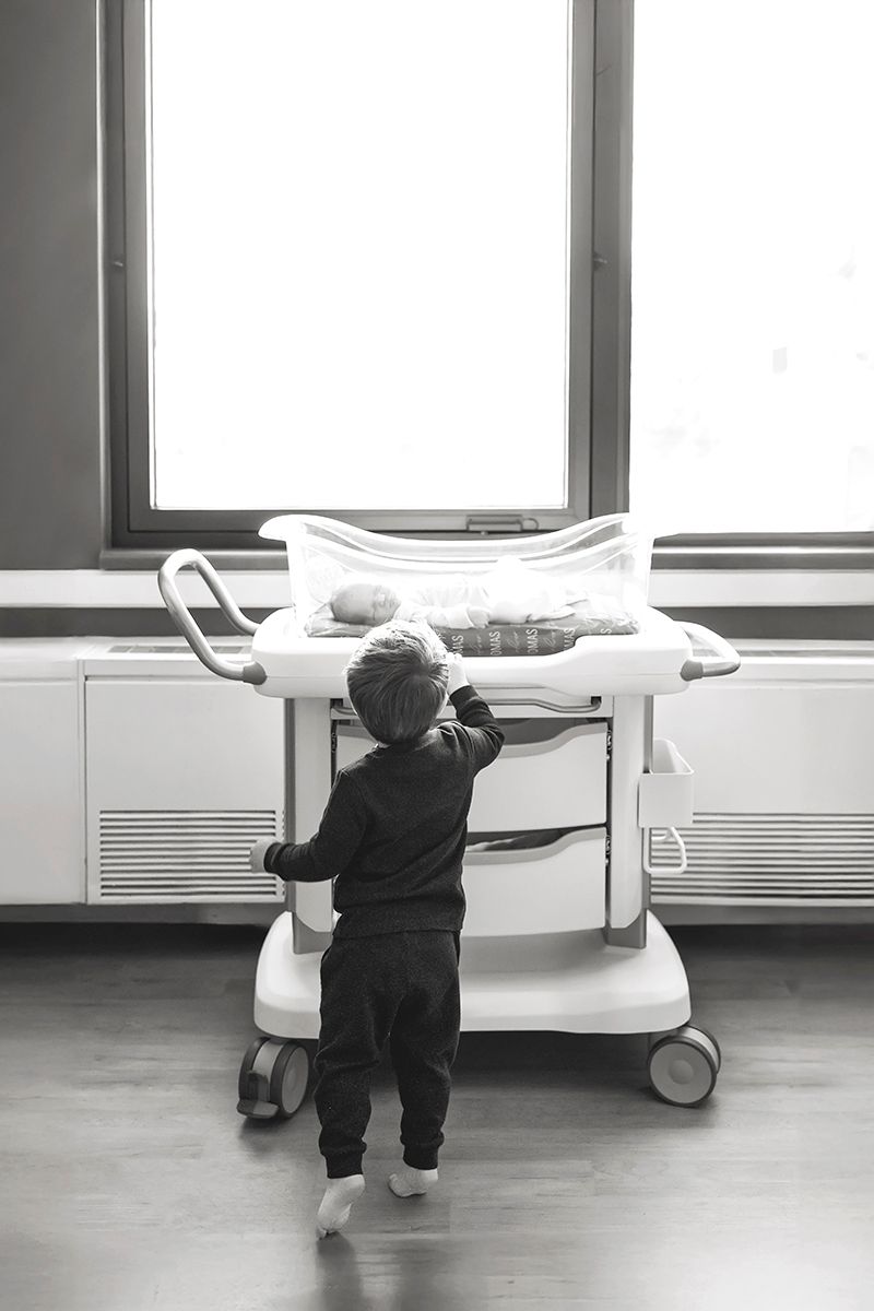 A sequence of black and white photos showing a person in dark clothing reaching up to touch a hospital bed rail.