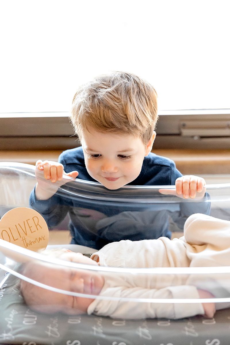 A child peeks through a clear plastic sheet with handwritten text visible.
