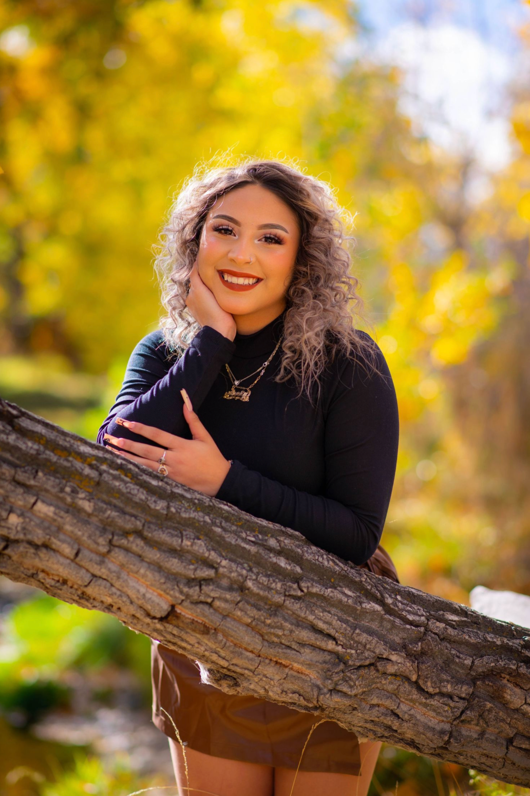 Cheerful autumn portrait session with person posing by rustic log.
