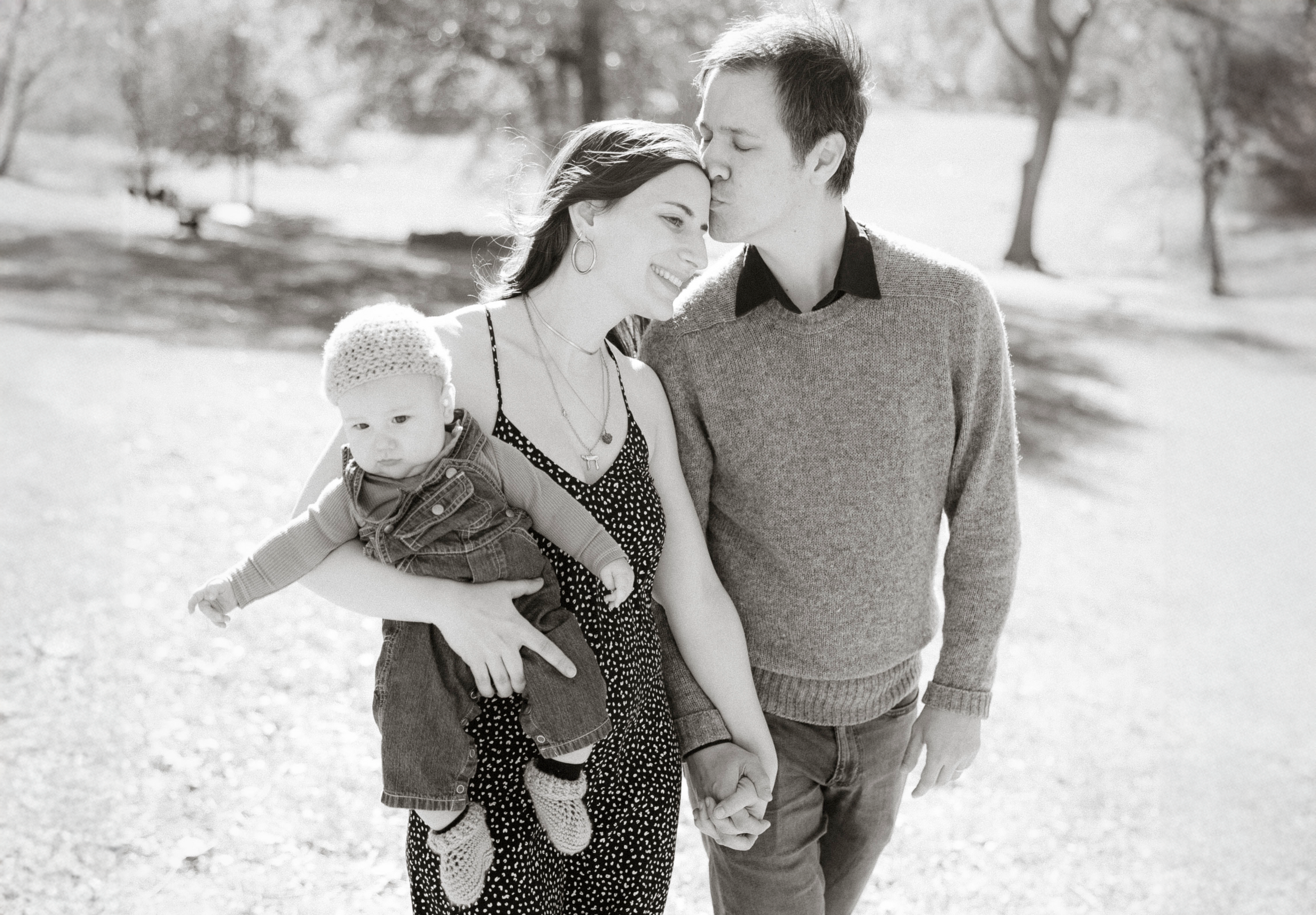 A black and white outdoor family portrait captured in a natural park setting.