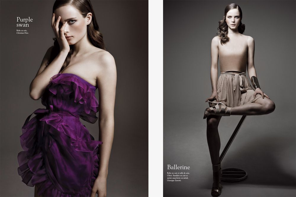 Fashion model poses in dramatic purple and black ruffled evening gown against dark studio backdrop.