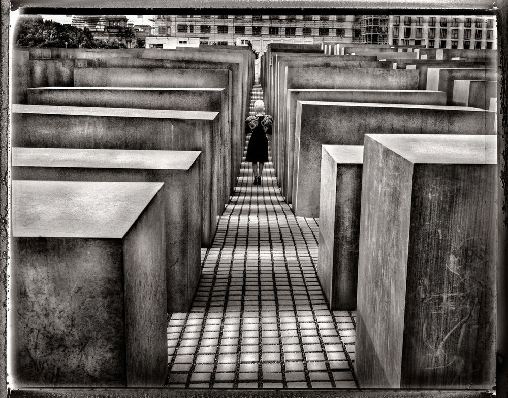 Black and white panoramic sequence showing a geometric path between wooden posts leading to a vanishing point.