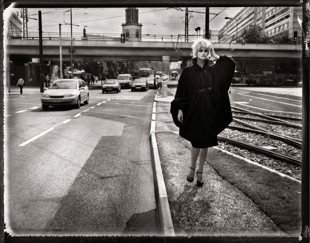 Black and white panoramic street scene showing urban infrastructure and pedestrians in moody lighting.