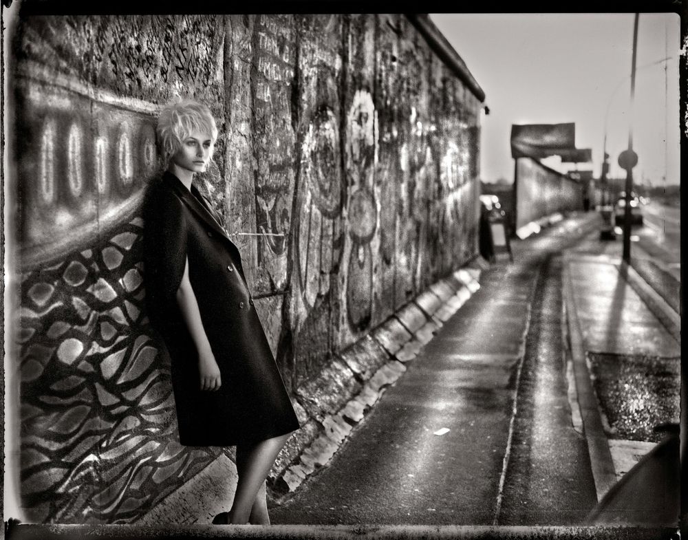 Black and white urban alleyway with graffiti walls and a figure walking in the distance, creating a moody atmosphere.