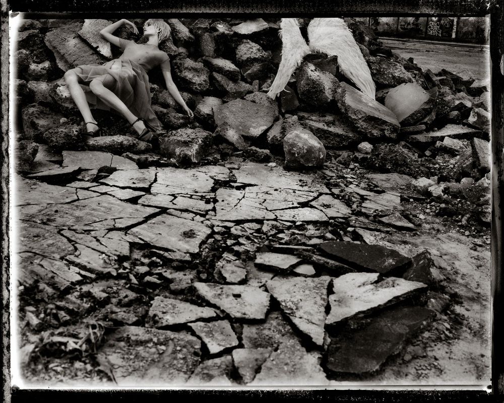 A black and white photograph shows a pile of debris and rubble scattered across the ground after destruction.