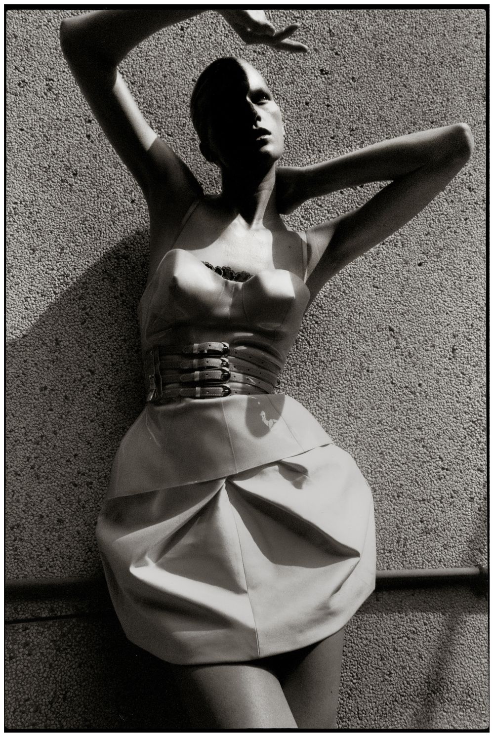 A black and white artistic photo series showing a figure in a white dress moving expressively against a textured wall.