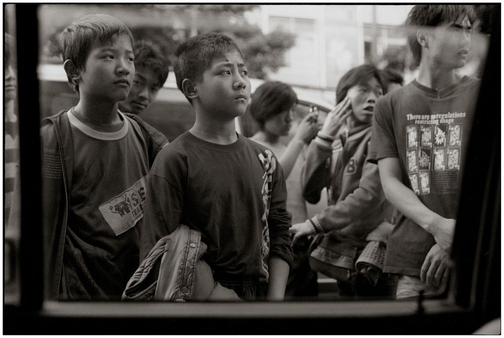 A group of children in black t-shirts gather together at an event, showing expressions of joy and excitement.