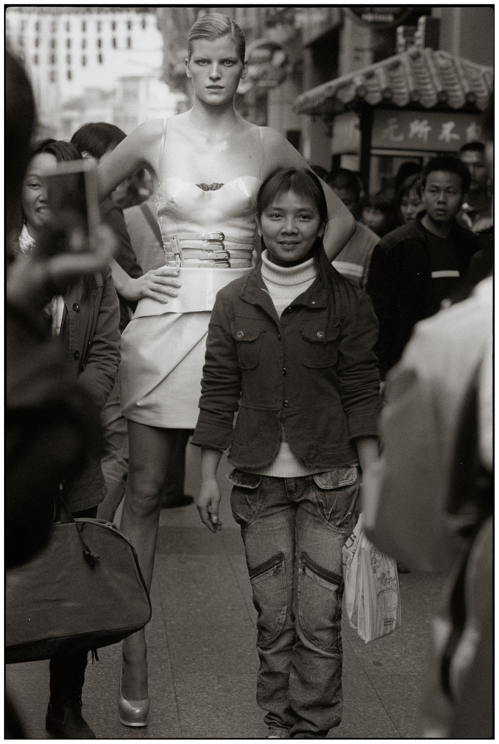 Black and white photograph showing cropped view of people's legs and torsos walking on a city street.
