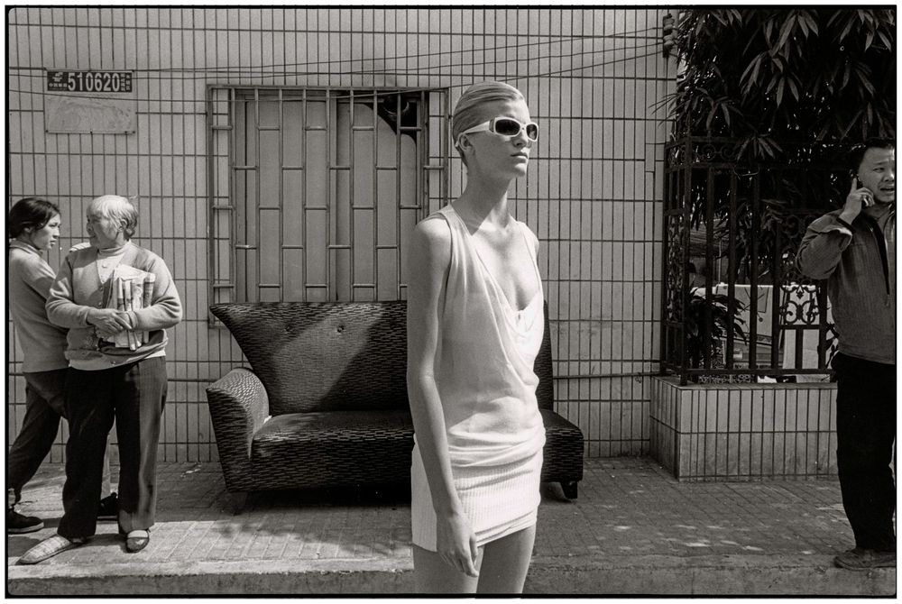 A series of black and white street photography images showing people in urban environments against walls and fences.