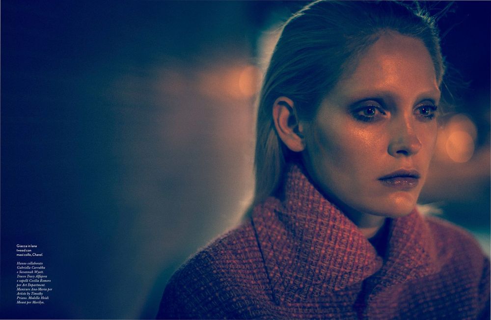 A portrait in moody lighting shows a person wearing a cozy turtleneck sweater against a dark background with bokeh effects.