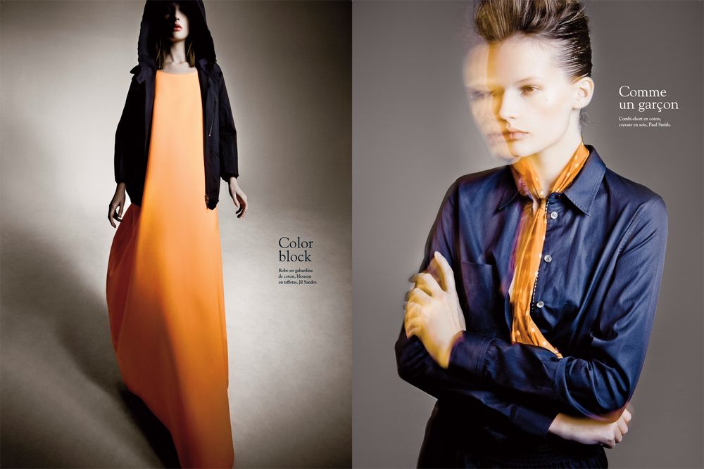 A fashion photo series showing a model in a navy blue blazer with contrasting orange fabric elements against a gray backdrop.