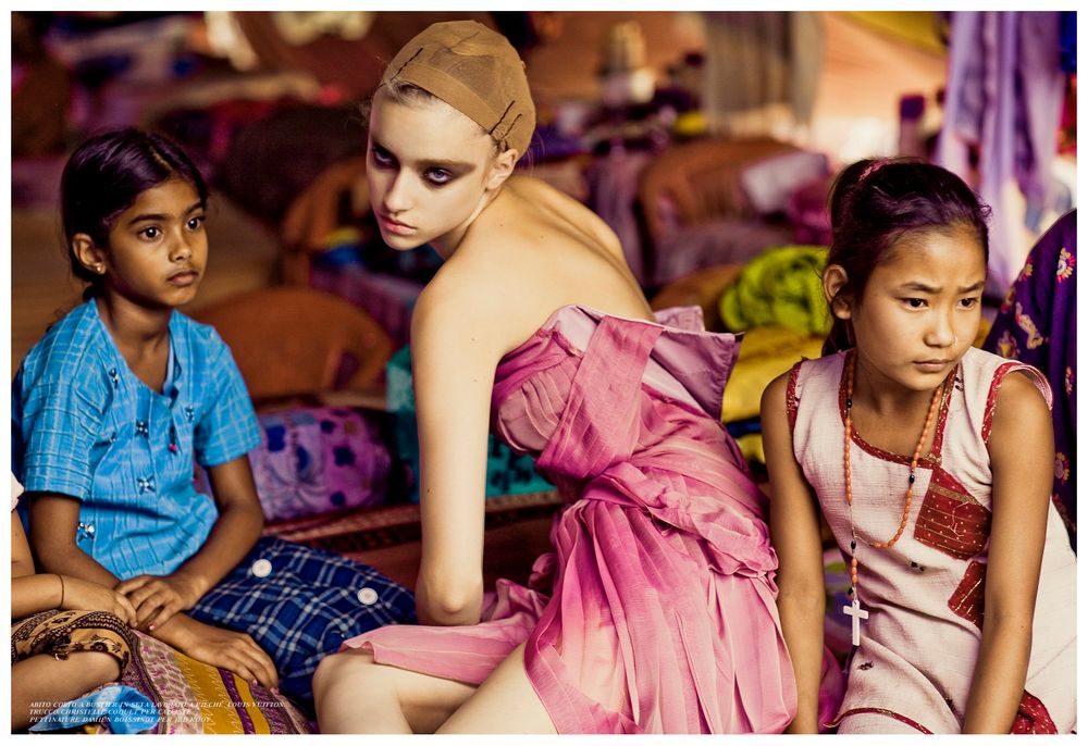 Children sit together in colorful traditional clothing at a community gathering in India.