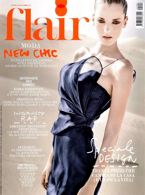 Fashion magazine cover featuring a model in an elegant navy blue asymmetrical evening gown against a soft ethereal background.