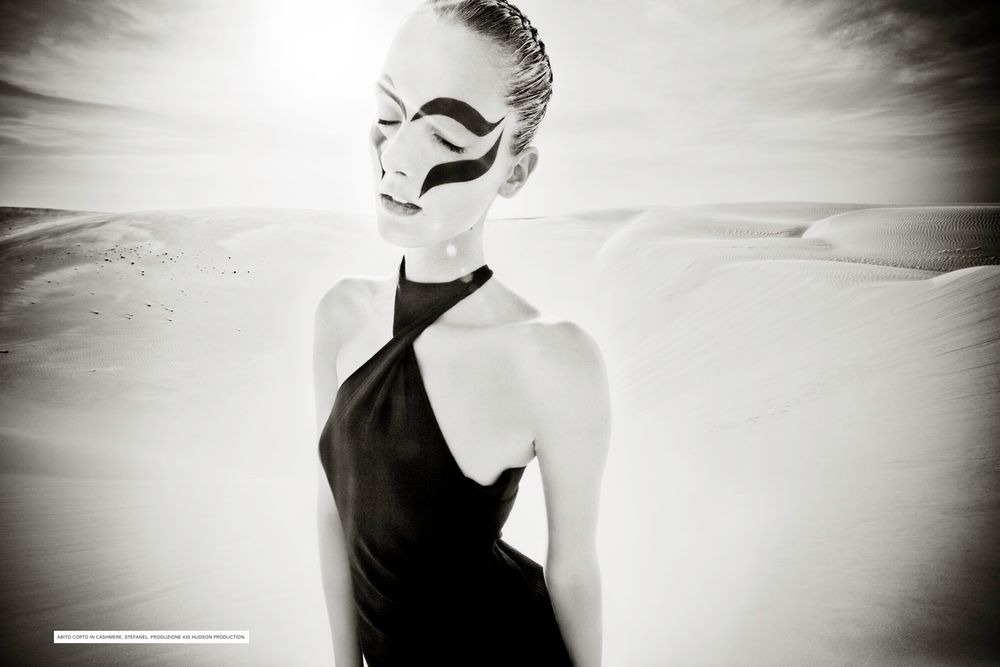 Artistic black and white portrait of a figure in a halter dress with dramatic lighting and ethereal atmosphere.