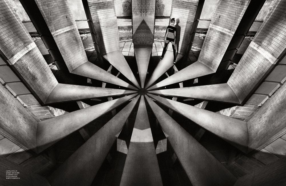 Black and white architectural photograph showing a circular pattern of industrial pipes and ducts converging to a central point.