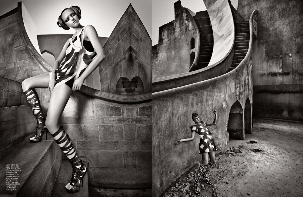 A surreal black and white art photograph featuring a figure in striped boots against a gothic architectural backdrop.