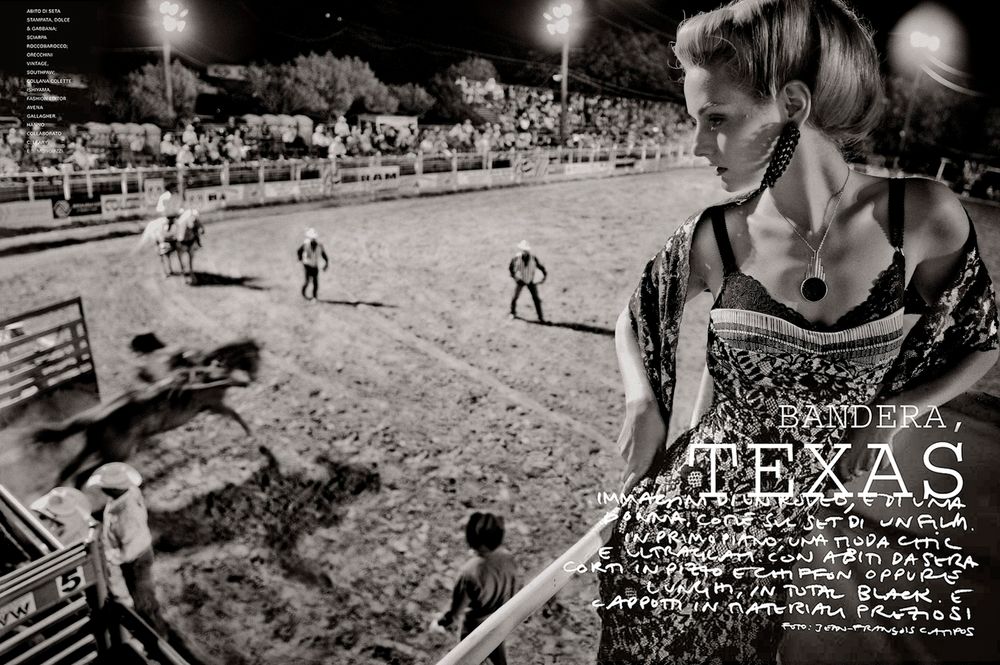 A black and white rodeo scene at night with riders in a dusty arena under floodlights.