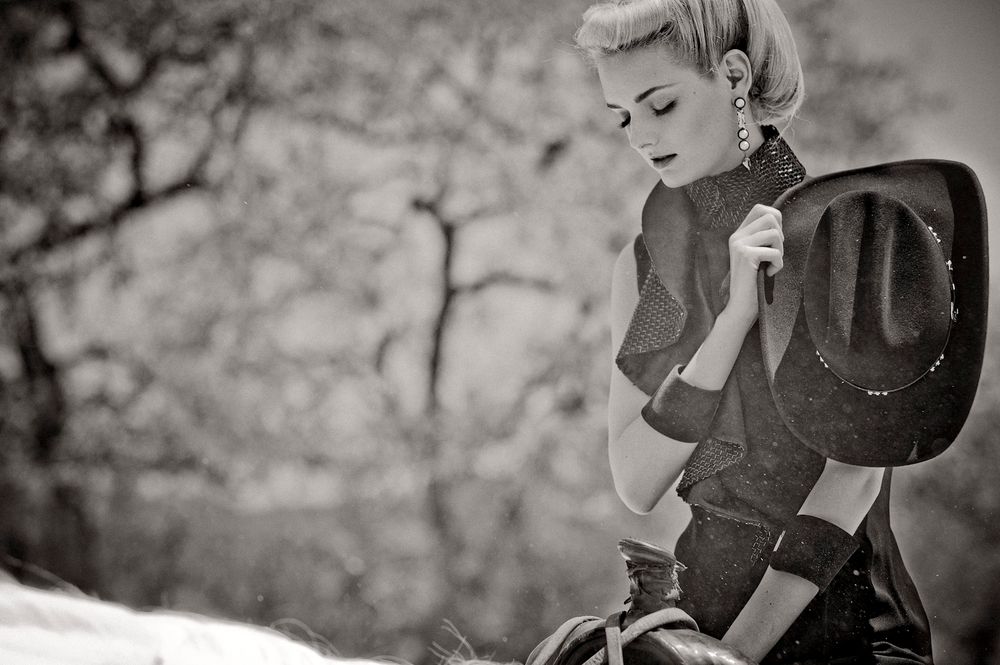 A black and white photo of a cowboy boot against a rustic background.