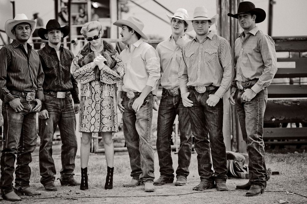 A line of young cowboys in western wear and boots standing together at a rodeo event.