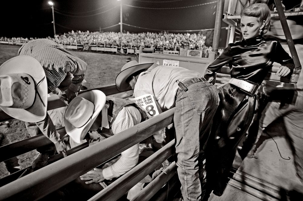 Black and white photograph of people sitting in stadium bleachers during an outdoor sporting event.