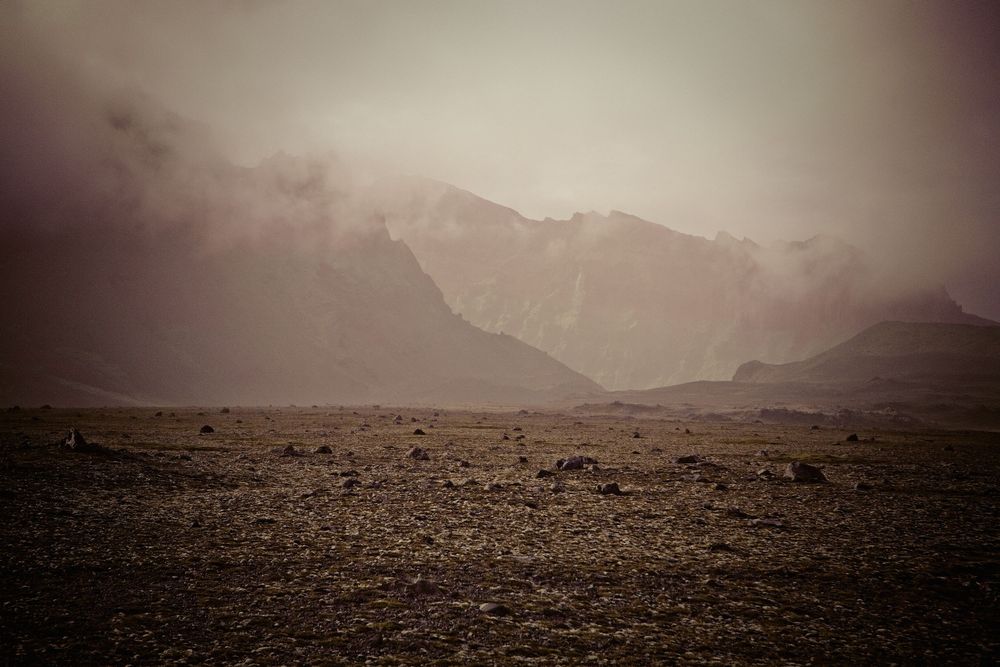 A panoramic series of misty mountain landscapes with barren terrain and dramatic cloudy skies in sepia tones.